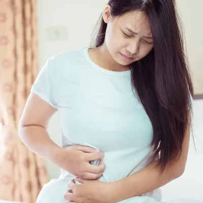 Mulher com a mão sobre a barriga, sentindo desconforto intestinal