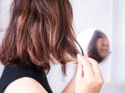 Mulher observando as pontas finas do cabelo com um espelho de mão