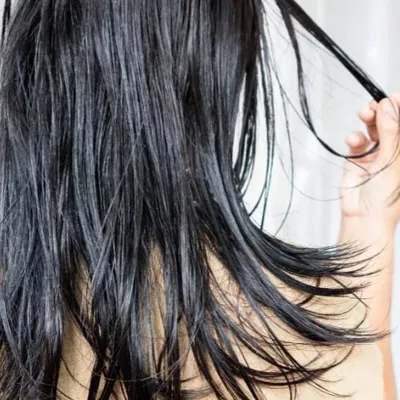 Mão segurando mechas de cabelo escuro e liso